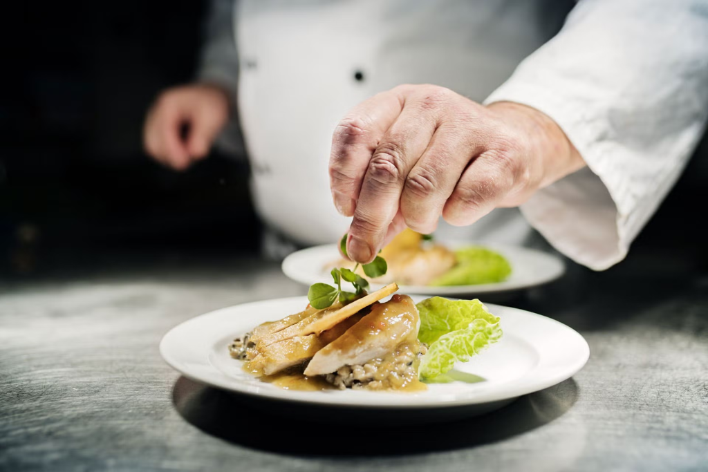 A chef placing a garnish on a fancy meal
